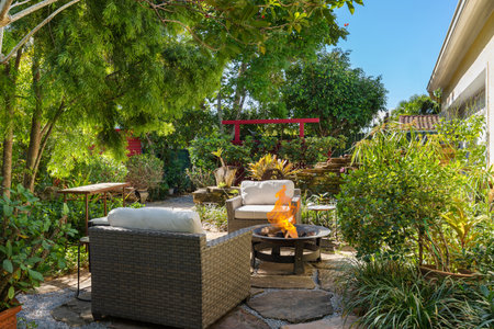 Beautiful garden with abundant vegetation, zen decorations, torii arch, fire pit, outdoor chairs, stone beds, palms, treesの写真素材