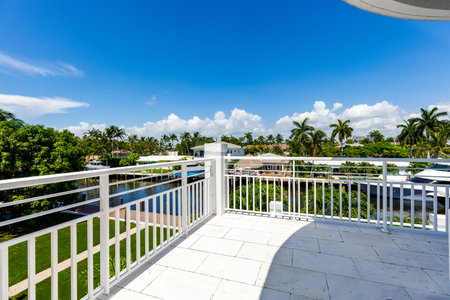 View from balcony to canal with boats in Miami neighborhood, with abundant vegetation, palms and tropical plants, swimming pool, white railingの写真素材