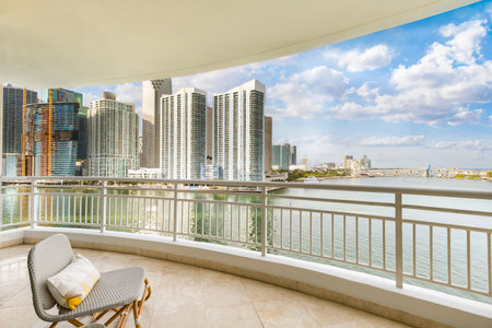 View from balcony on Brickell Key island in Miami, modern buildings and towers, boats, bridges, sea, outdoor chairs, white railingの写真素材