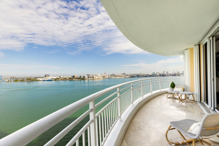 View from balcony on Brickell Key island in Miami, modern buildings and towers, boats, bridges, sea, outdoor chairs, white railingの写真素材