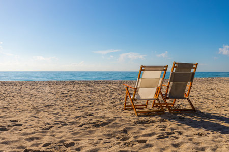 Beautiful tropical landscape with chairs, sand, ocean view with horizon, sunny sky, tranquility and relaxation.の写真素材
