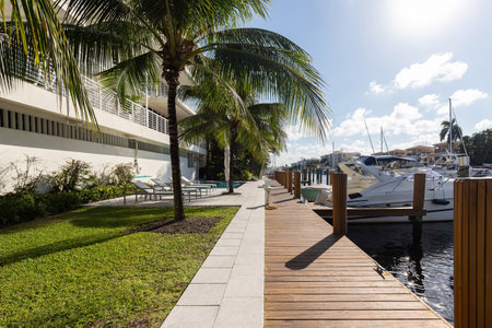View from the pier in the Nurmi Isles neighborhood in Fort Lauderdale, canals with boats everywhere, swimming pool, sun loungers, houses and modern buildings, tropical climate withの写真素材
