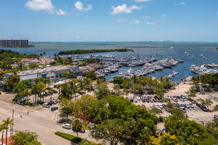 Aerial drone shot of Grovenor House Coconut Grove in Miami, abundant tropical vegetation around, modern buildings and towers, blue sky with clouds and city in the backgroundの写真素材