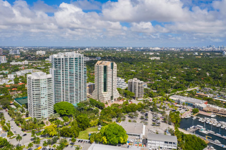 Aerial drone shot of Grovenor House Coconut Grove in Miami, abundant tropical vegetation around, modern buildings and towers, blue sky with clouds and city in the backgroundの写真素材