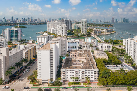 Point of view of swimming pool in the West bay building, in Miami, with red brick floor, tropical plants around, balconies, umbrellas with sun loungers, blue skyの写真素材