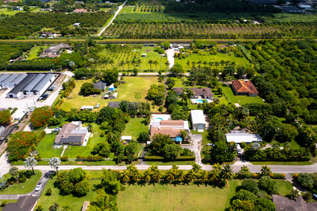 Aerial drone shot, in a rural area of Miami, with houses and warehouses on large lots, with a large amount of greenery around, tropical plants, plantations and rural landscape in tの写真素材