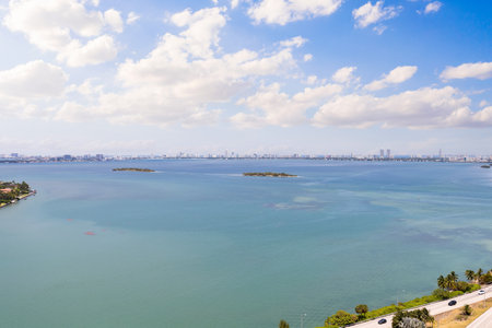 Aerial shot from balcony of suburb in Edgewater, view of Biscayne Bay, with large tropical vegetation around, modern houses and towers, commercial areas, summer weather, blue skyの写真素材