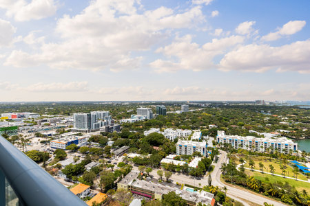 Aerial shot from balcony of suburb in Edgewater, view of Biscayne Bay, with large tropical vegetation around, modern houses and towers, commercial areas, summer weather, blue skyの写真素材
