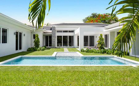 Backyard of elegant and modern house, located in Glenvar Heights, in Miami-Dade, white walls, black tiles, glass doors, short cepes, T-shaped pool, trees and palm trees around, sunの写真素材
