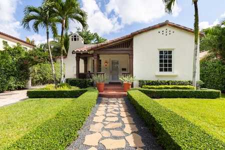 Facade of a colonial-style house with a beautiful front garden, with a path to the main door, driveway, tiled roof, located in the Granada neighborhood in the city of Coral Gables,の写真素材