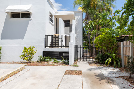 Front of modern house in Coral way neighborhood in Miami, driveway, stairs, palms, cyan walls, wooden fence, blue sky in the backgroundの写真素材