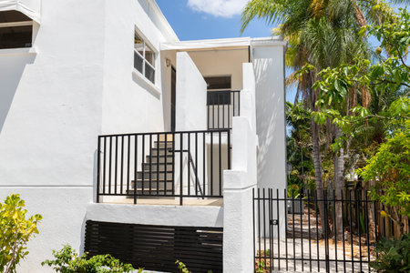 Front of modern house in Coral way neighborhood in Miami, driveway, stairs, palms, cyan walls, wooden fence, blue sky in the backgroundの写真素材