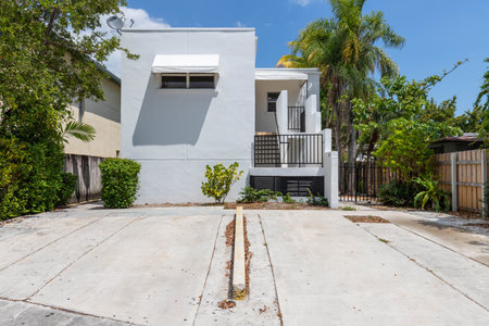 Front of modern house in Coral way neighborhood in Miami, driveway, stairs, palms, cyan walls, wooden fence, blue sky in the backgroundの写真素材