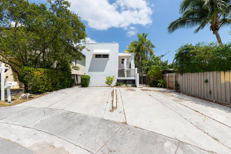 Front of modern house in Coral way neighborhood in Miami, driveway, stairs, palms, cyan walls, wooden fence, blue sky in the backgroundの写真素材