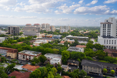 Aerial drone shot of Little Gables neighborhood in Miami, suburban area with lots of buildings and houses, large tropical vegetation, horizon line with blue sky with cloudsの写真素材