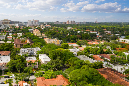 Aerial drone shot of Little Gables neighborhood in Miami, suburban area with lots of buildings and houses, large tropical vegetation, horizon line with blue sky with cloudsの写真素材