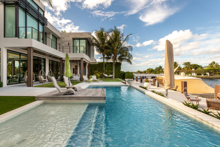USA. Modern building with swimming pool, trees, chairs. Urban landscape with blue reflecting pool, city architecture, and scenic environment.の写真素材