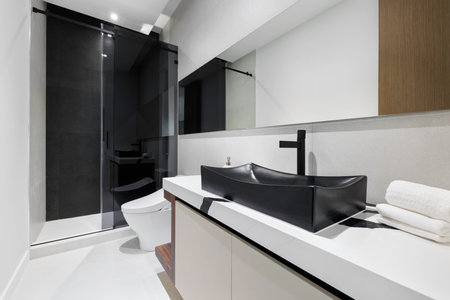 Beautiful photos of the interior of a Building. Clean, modern bathroom with refreshing shower, reflecting mirror, and sleek tiles.の写真素材