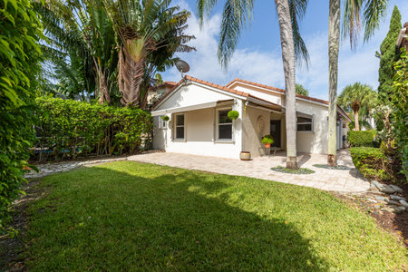 beautiful house in tropical garden with palm trees and green lawn.の写真素材