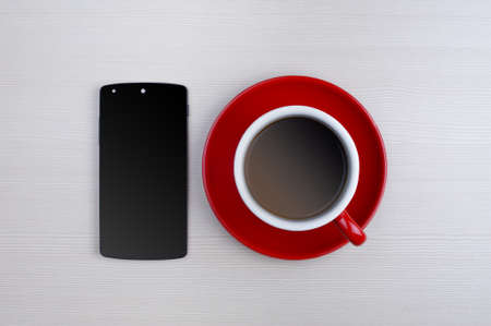 Coffee cup and smartphone on wooden table. View from aboveの写真素材