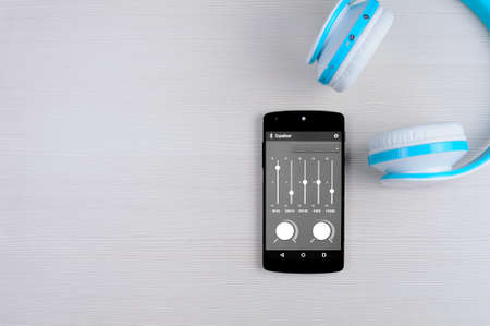 Smartphone and headphones on a wooden table. Top view.の写真素材