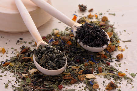 assortment of dry tea in spoons, on wooden backgroundの写真素材