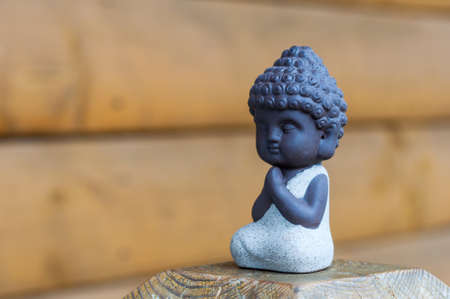 Little Buddha pray or meditate on wooden background with empty space. Praying and meditation, yoga concept.の写真素材