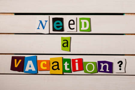 Need a vacation - written with color magazine letter clippings on wooden board.の写真素材