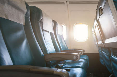 Empty aircraft seats and windows with sun light.