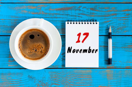 November 17th. Day 17 of month, calendar on notepad near white coffee cup at blue wooden workplace background. Autumn time.の写真素材