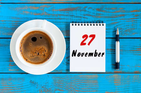November 27th. Day 27 of month, loose-leaf calendar and white coffee cup at college professor...
