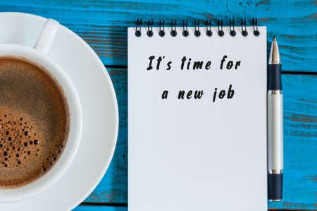 time for new job - inscription in notepad near morning coffee mug at blue wooden table.の写真素材