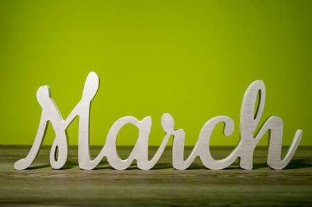 Close Up March word carved out of wood on green background. Spring beginning conceptの写真素材