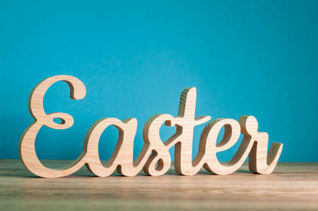 Easter - carved wooden text at blue background. Festive decoration. Happy Easter conceptの写真素材