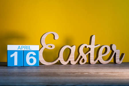 Easter 2017 - April 16th. Calendar and carved of wooden text Easter at yellow background. Holiday concept.の写真素材