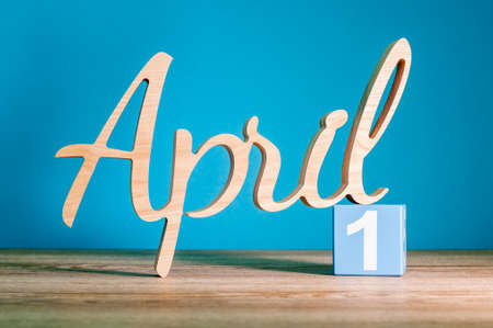 April 1st. Day 1 of month, calendar on wooden table and green background. Spring time, empty space for textの写真素材