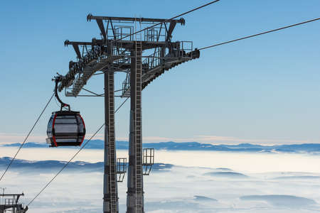 Gondola lift. Cabin of ski-lift in the ski resort in the early morning at dawn with mountain peak in the distance. Winter snowboard and skiing conceptの写真素材