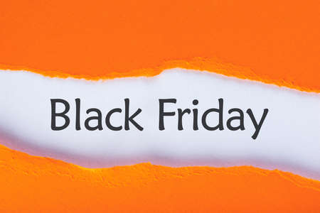 Message appearing behind ripped orange paper with Black Friday Sale text. Shopping time. Day with biggest Sale. Mockup.の写真素材