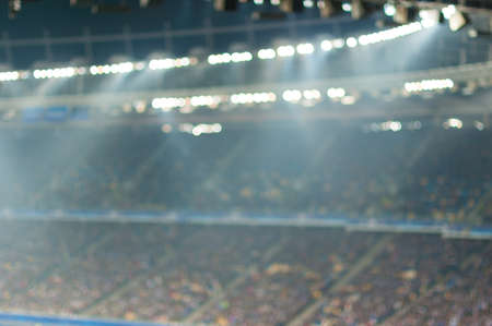 Blurred soccer stadium or ather sport arena at night with projector and stands full of people, fans, crowdの写真素材