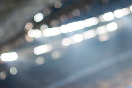 Blurred soccer stadium or ather sport arena at night with projector and stands full of people, fans, crowdの写真素材