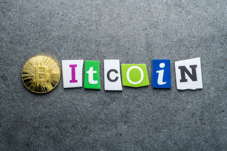 Golden bitcoin and text BITCOIN with carved letters on grey background. Virtual, cryptocurrency invest conceptの写真素材