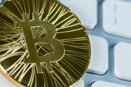 Golden bitcoin coin against keyboard. Digital money and cryptocurrencies concept