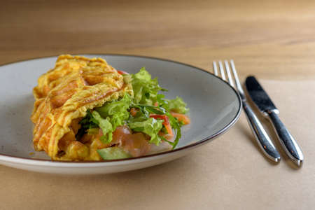 Omelette with mushrooms and salad. Home omelette with fried mushrooms, salmon, fresh leaves of Iceberg on a plate and vintage wooden table. Stuffed vegetarian omelette idea. Rustic styleの写真素材