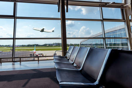 View from the airport lounge to plane taking off, passenger aircraft in the sky. Airplane travel...