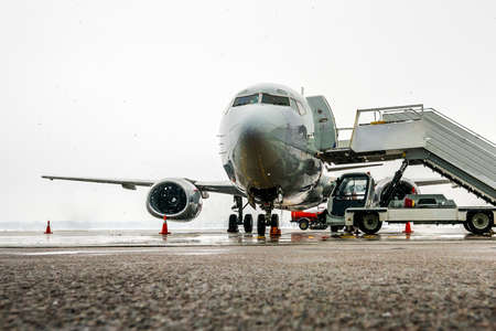 Airplane with a ladder waiting for passengers. Boarding is delayed due to bad weather. Flight...