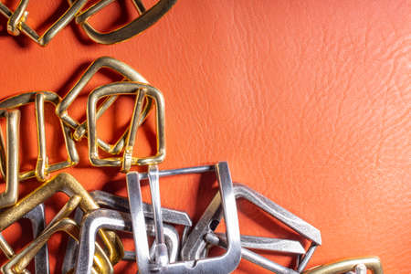 Belt buckles on red full grain leather background. Materials, accessories on leather craftmans work...