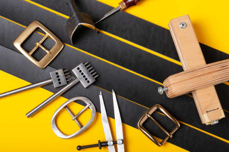 Belt buckles with leather tools on black full grain leather background. Materials, accessories on...