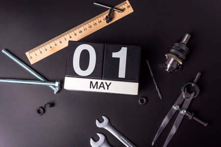 Labour day. May 1st. Day 1 of may month, calendar on black background with workers toolsの写真素材