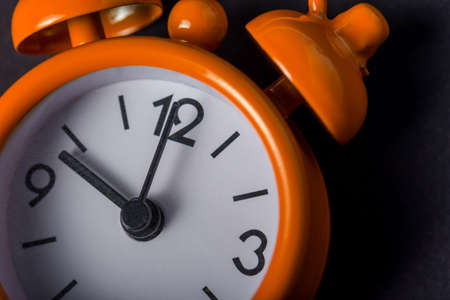 Bright orange Clock on black background. Vintage alarm clock. Concept of Time management.の写真素材