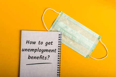 How to get Unemployment benefits. Message at notepad with face mask. Coronavirus Covid-19 lockdown conceptの写真素材
